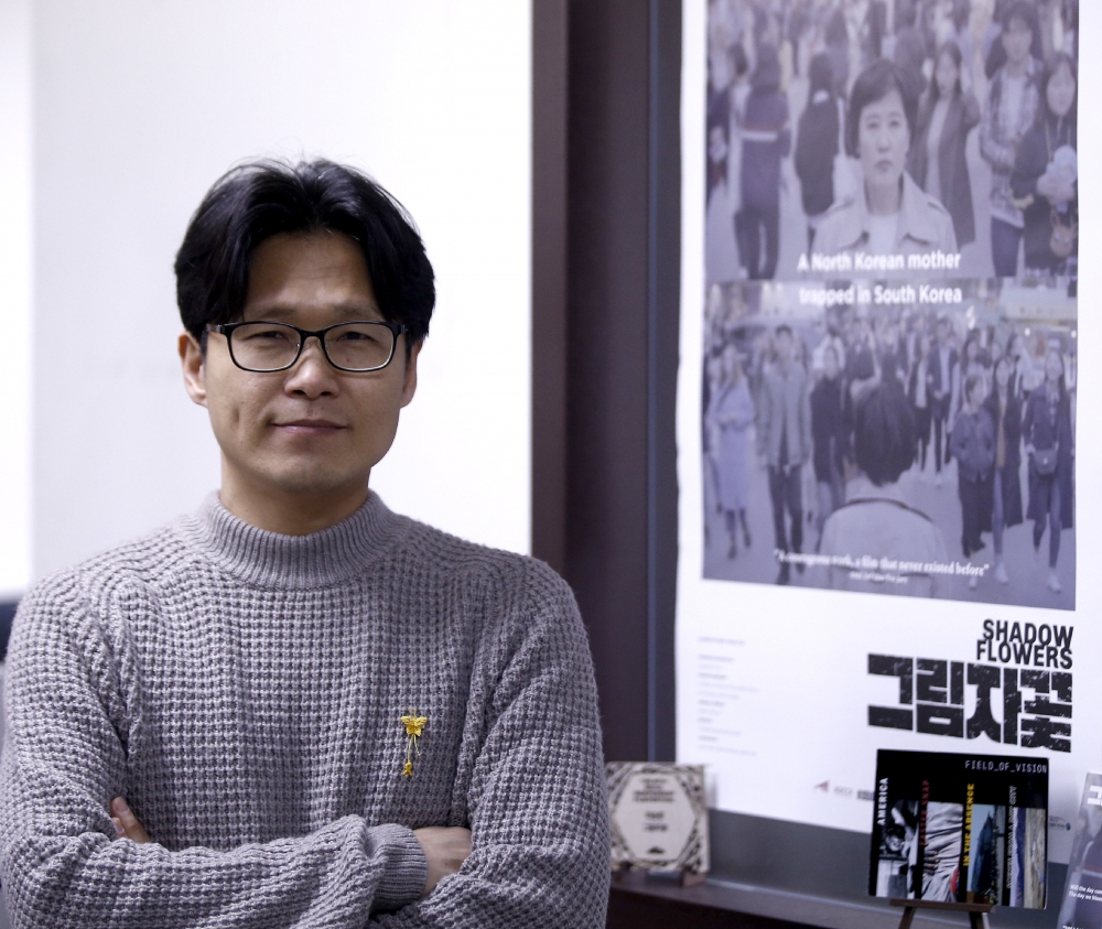 ▲ 이승준 감독이 자신의 최신 작품 '그림자꽃' 포스터 옆에 서 있다. /이성철 기자 slee0210@incheonilbo.com