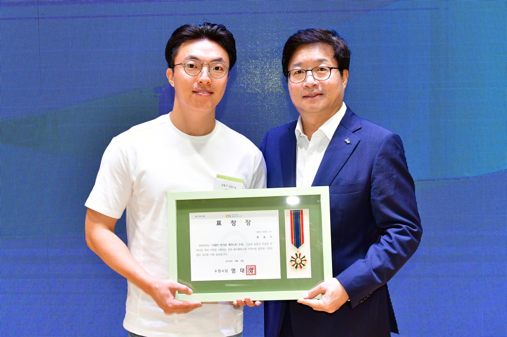 ▲ 류광현(왼쪽)씨가 수원시로부터 선행시민 표창을 받고 염태영 시장과 기념사진을 찍었다. /사진제공=수원시