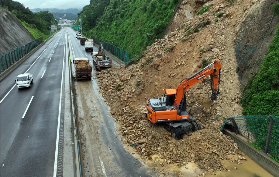 ▲ 지난 18일 경기도 용인시 처인구 포곡읍 수도권제2순환고속도로 봉담 방면 금어2교 부근 2차로 도로 옆 경사면 토사가 흘러내리며 도로가 통제돼 관계자들이 복구작업을 하고 있다. /사진제공=연합뉴스