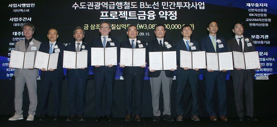 ▲ 15일 서울시 영등포구 콘래드 호텔에서 열린 수도권 광역급행철도 B노선 민간투자사업 프로젝트금융 약정식에서 정상혁 신한은행장(왼쪽 네 번째), 김보현 대우건설 대표이사(왼쪽 다섯 번째), 김정훈 지티엑스비㈜ 대표이사(왼쪽 여섯 번째) 등 관계자들이 기념사진을 촬영하고 있다. /사진제공=신한은행