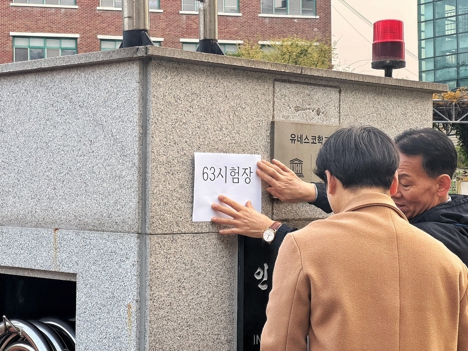 ▲ 13일 오전 2026학년도 대학수학능력시험이 실시되는 인천 남동구 인천남고등학교 현수막에 시험자이 잘못 기재돼 관계자들이 시험장 명을 정정하고 있다. /홍준기 기자 hong@incheonilbo.com